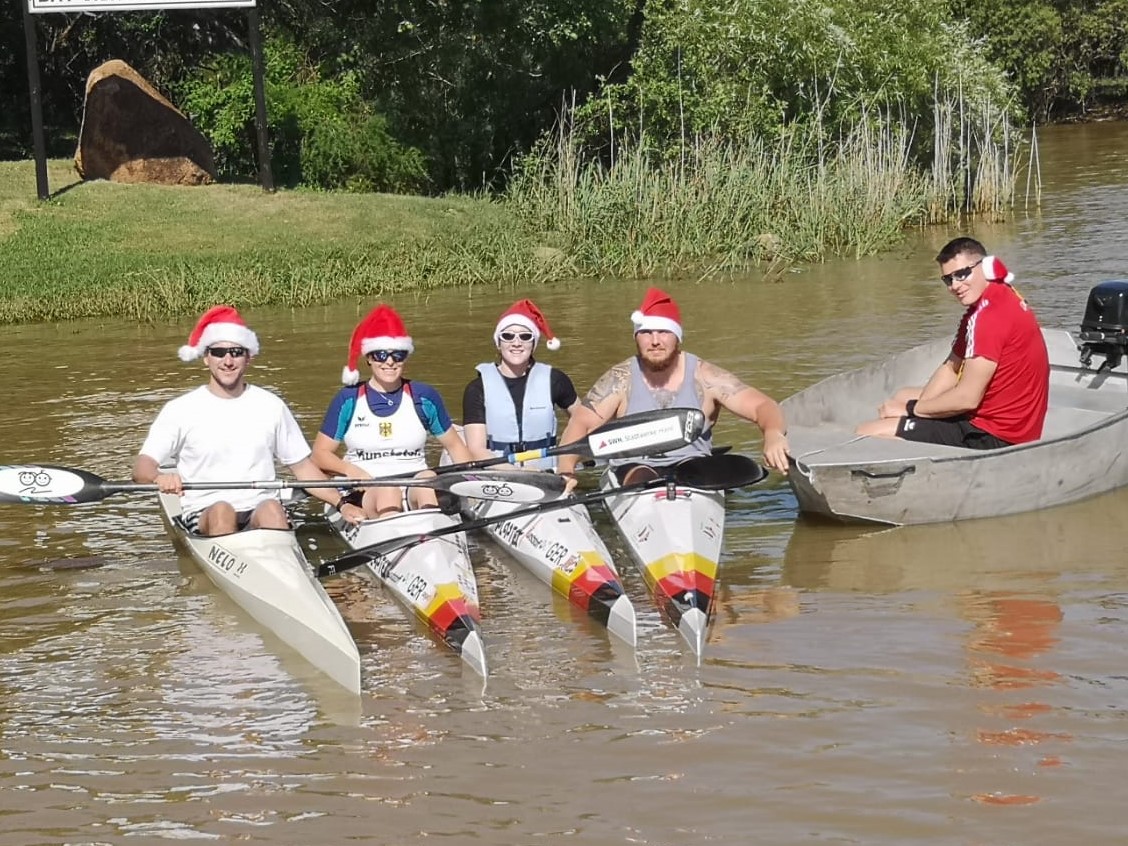 Vier Parakanuten in Ihren Kanus und Ihr Trainer in einem Boot tragen Weihnachtsmürtzen und sommerliche Keidung bei Sonnenschein | Foto: Team