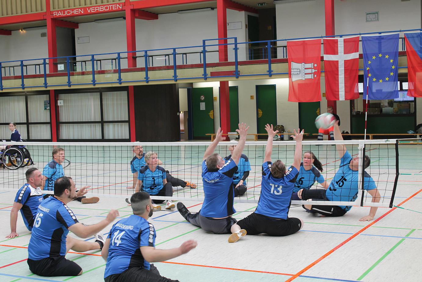 Zwei Sitzvolleyballspieler sitzen vor dem Netz und versuchen den geschmetterten Volleyball zu blocken. | Foto: T.H.-Eilbeck